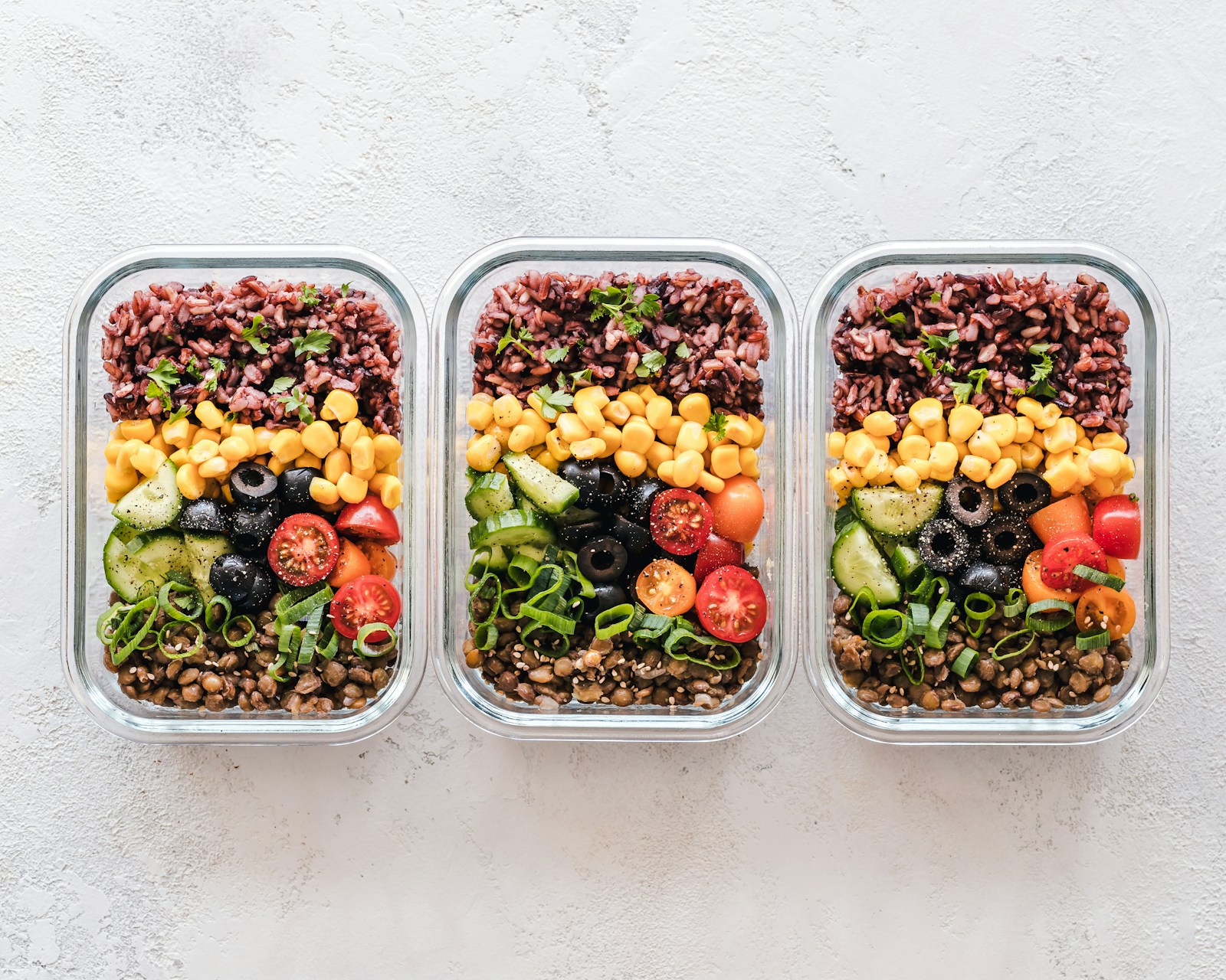 Prepared meals with grains and fresh vegetables in three containers